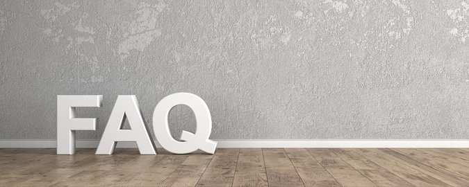 Brauner Holzleistenboden vor grau gesprenkelter Wand, weiße Holzbuchstaben "FAQ" an der Wand lehnend