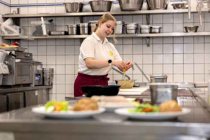 Eine Köchin bereitet Gerichte in der Küche des Copa-Restaurants zu.