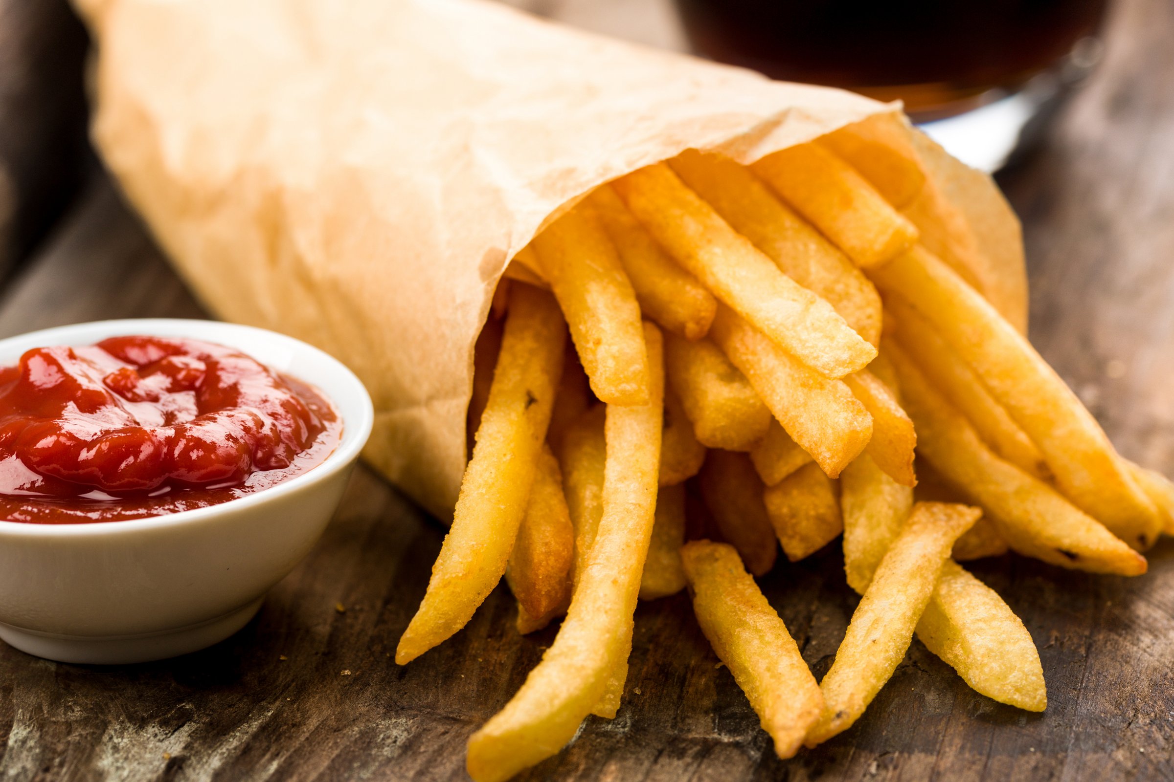 Pommes im Kiosk des Copa Ca Backum Eine Tüte Pommes liegt neben einem kleinen Porzellanschälchen, das mit Ketchup gefüllt ist.
