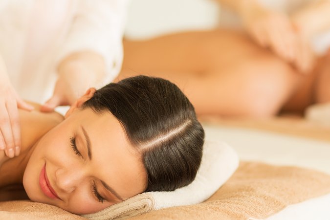 Paarmassagen in der Copa Oase Ein Paar liegt oberkörperfrei mit dem Bauch auf einer Liege und lässt sich massieren