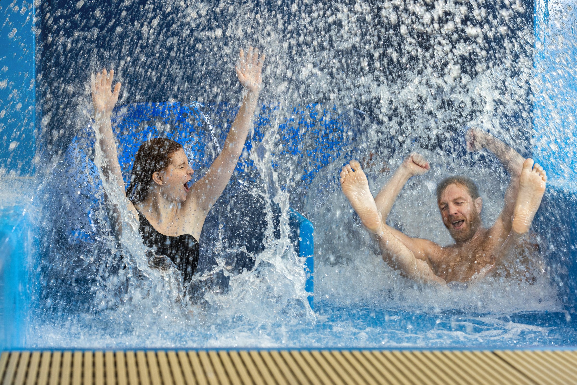 Rutschspaß in der Racerrutsche des Copa Ca Backum Mann und Frau kommen voller Freude aus einer Rutsche mit zwei Bahnen.