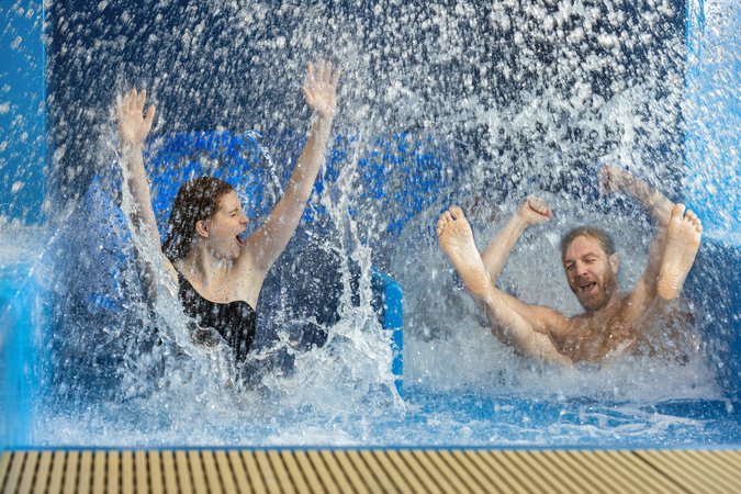 Rutschspaß in der Racerrutsche des Copa Ca Backum Mann und Frau kommen voller Freude aus einer Rutsche mit zwei Bahnen.