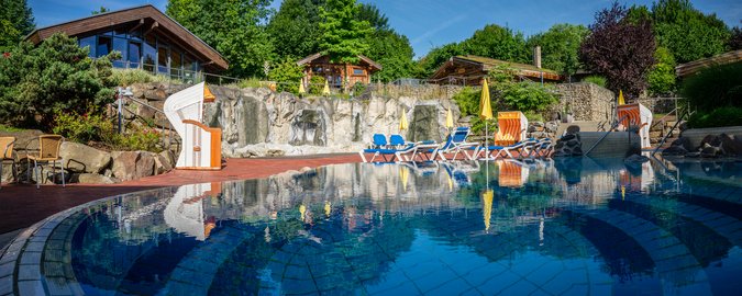 Viele Saunahäuser, davor ein blaues Entspannungsbecken im Saunagarten