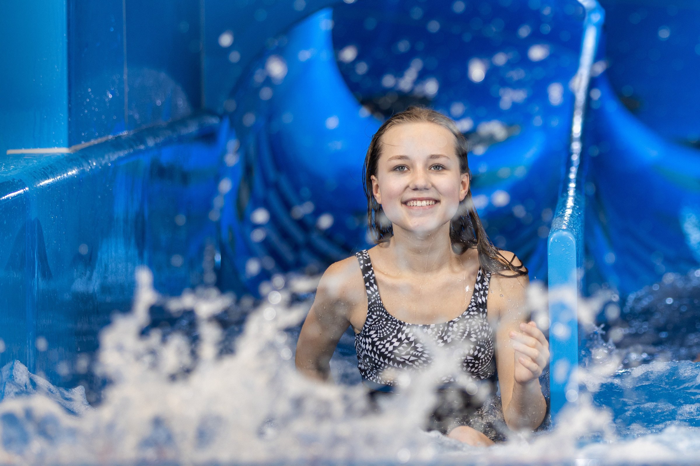 Ein Mädchen kommt aus einer Wasserrutsche gerutscht.