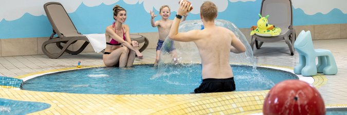 Mutter und Vater spielen mit Kind im Wasser