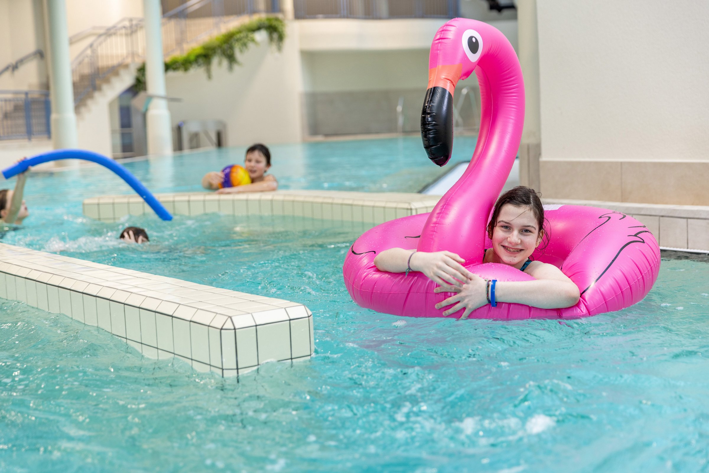 Mädchen lächelt in ihrem Flamingo-Schwimmring im Strömungskanal